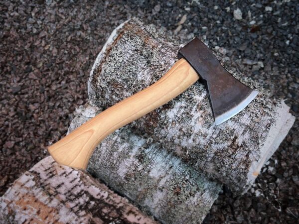 The Swit carving axe resting on stone in a forest — spoon carving hatchet. Retsing on a pile of logs